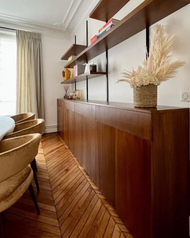 Salle à manger structurée par un meuble bas en bois foncé, lignes épurées et matériaux contrastés